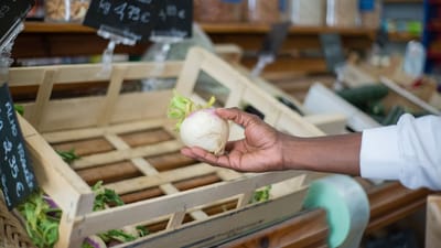 Gros plan sur une main sélectionnant un navet frais dans une caisse en bois au marché portugais.