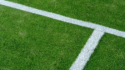 Vue détaillée des lignes blanches sur la surface en gazon vert d'un court de tennis.