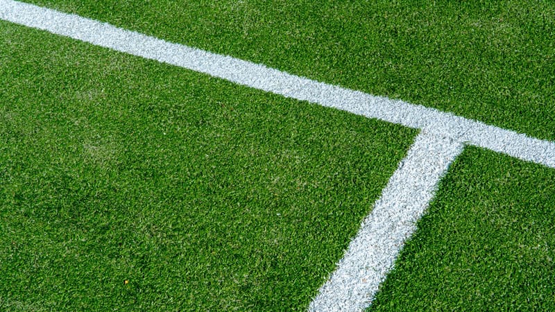 Vue détaillée des lignes blanches sur la surface en gazon vert d'un court de tennis.