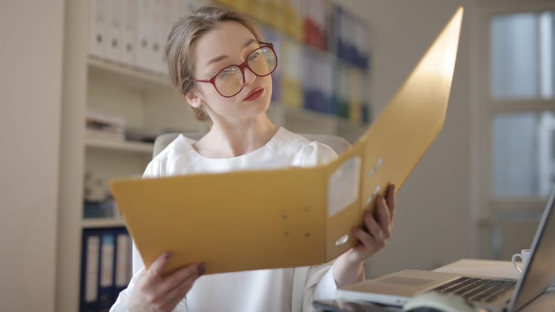 Femme caucasienne lisant attentivement des documents dans un bureau.