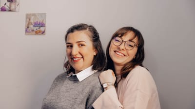 Deux femmes joyeuses, souriantes et s'embrassant, capturant un moment d'amitié à l'intérieur.