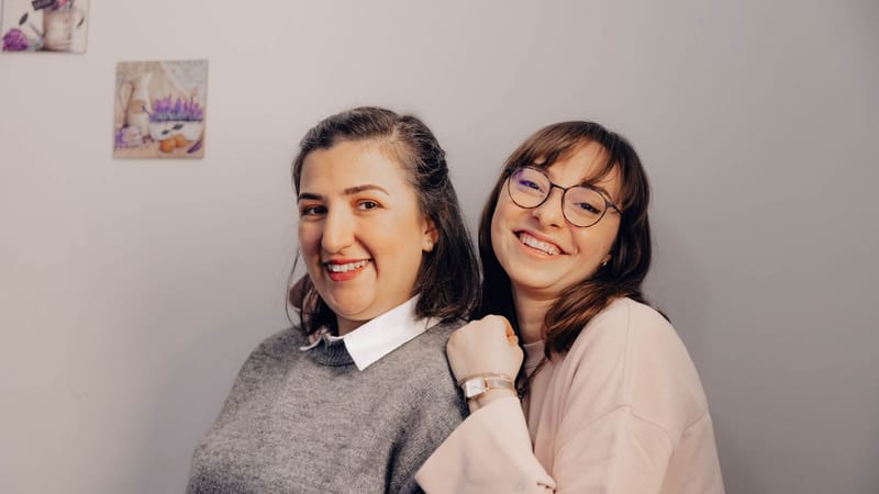 Deux femmes joyeuses, souriantes et s'embrassant, capturant un moment d'amitié à l'intérieur.