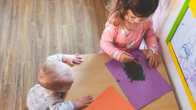 Deux jeunes enfants peignant avec des couleurs vives à la maison. Capturé de haut.