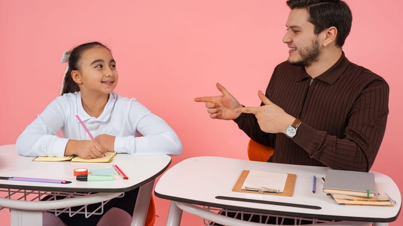 Scène de classe engageante avec un enseignant et un élève partageant une conversation aux bureaux.