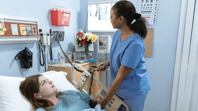 Infirmière prodiguant des soins à un patient dans une chambre d'hôpital avec du matériel médical.