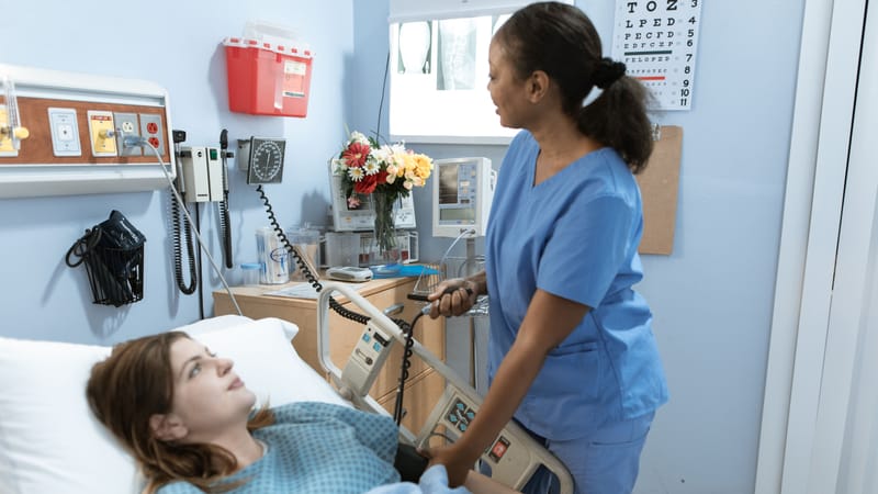 Infirmière prodiguant des soins à un patient dans une chambre d'hôpital avec du matériel médical.