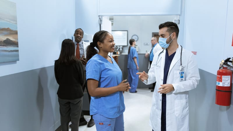 Médecins et infirmiers dans un couloir d'hôpital discutant de questions médicales.