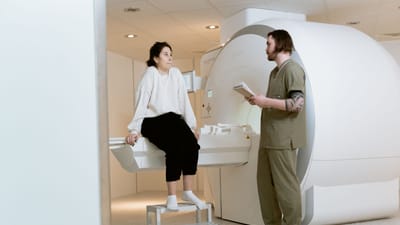 Un patient consulte un technicien dans une salle d'IRM moderne, mettant en avant des installations de santé avancées.