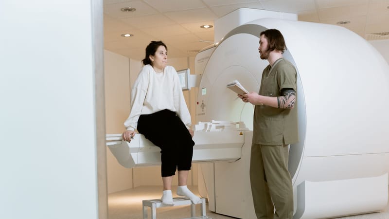 Un patient consulte un technicien dans une salle d'IRM moderne, mettant en avant des installations de santé avancées.
