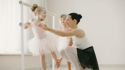 Une professeur de ballet guide de jeunes ballerines lors d'une séance d'entraînement au barre.