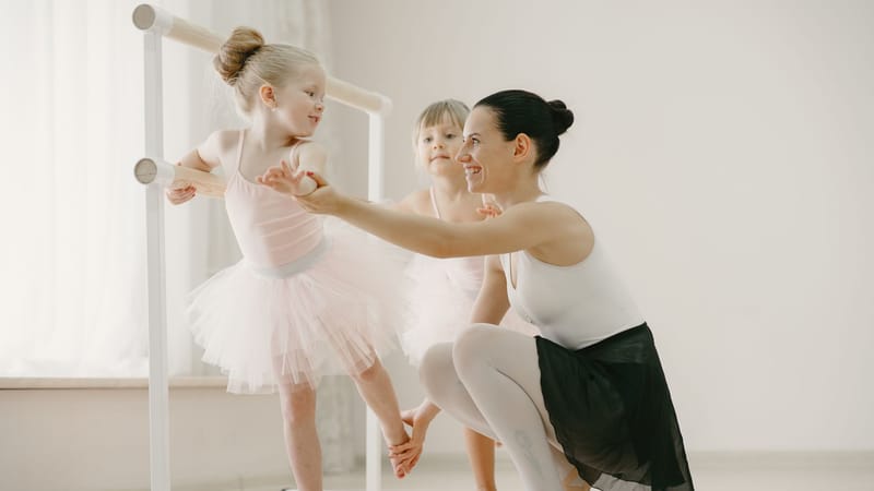 Une professeur de ballet guide de jeunes ballerines lors d'une séance d'entraînement au barre.