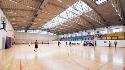 Vue en grand angle d'un terrain de basket intérieur avec des joueurs s'entraînant et participant à des activités sportives.