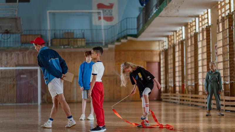 Des enfants pratiquant la gymnastique dans une salle de sport avec leur enseignant.