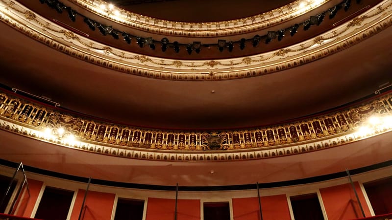 Intérieur de théâtre richement décoré avec des détails dorés et un éclairage spectaculaire.