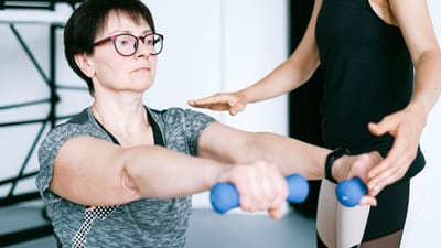 Un entraîneur personnel guide une femme dans des exercices avec des haltères pour le fitness et le renforcement musculaire.