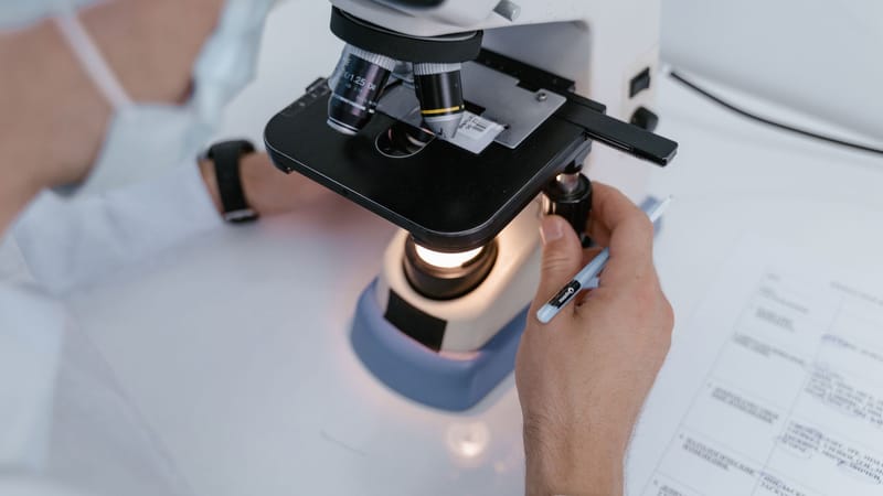 Gros plan d'un scientifique examinant des échantillons sous un microscope dans un laboratoire.