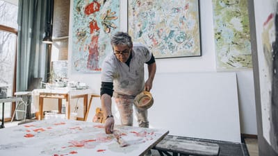 Un peintre masculin talentueux travaillant dans son atelier d'art, entouré de peintures abstraites.