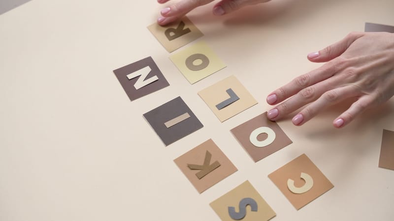 Gros plan sur des mains arrangeant des lettres sur du papier coloré, parfait pour des concepts de design.