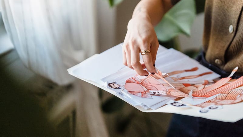 Un designer de mode examinant des croquis colorés dans un environnement de studio bien éclairé.