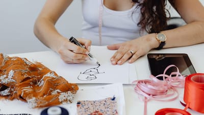 Designer de mode esquissant des idées avec des échantillons de tissu et des outils sur sa table.