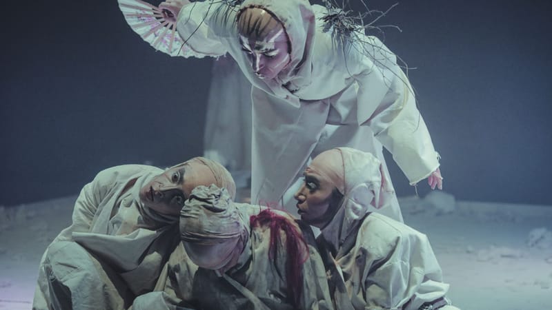 Des artistes en costumes élaborés sur scène lors d'une pièce de théâtre, créant une scène artistique et dramatique.