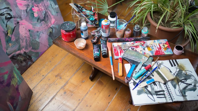 Fournitures d'art colorées et peintures abstraites dans un cadre confortable de studio d'artiste.