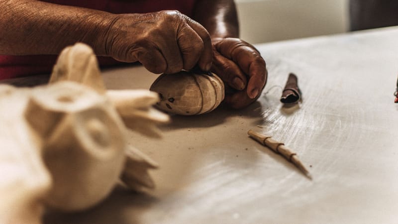 Gros plan détaillé sur des mains sculptant habilement du bois en une sculpture, mettant en valeur l'artisanat traditionnel.
