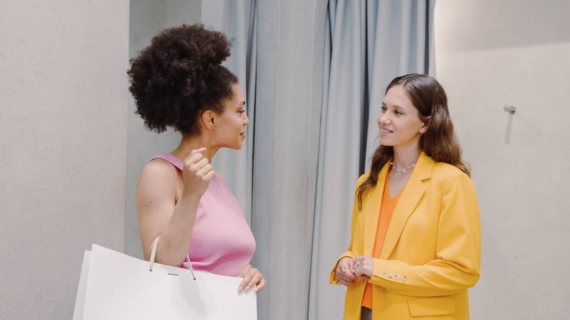 Deux femmes discutant de mode et de style dans un magasin de vêtements, à l'intérieur.