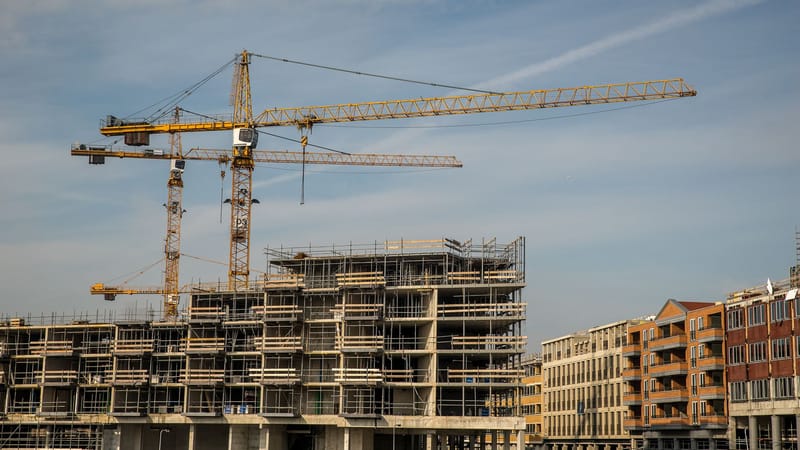 Chantier de construction en ville avec des grues et des structures partiellement construites sous un ciel dégagé.