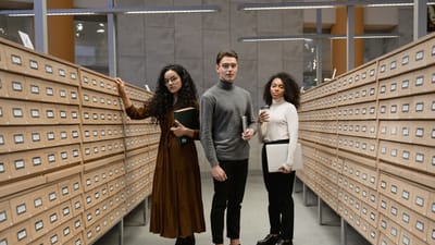 Trois étudiants divers effectuant des recherches dans le centre de catalogage de cartes d'une bibliothèque moderne.