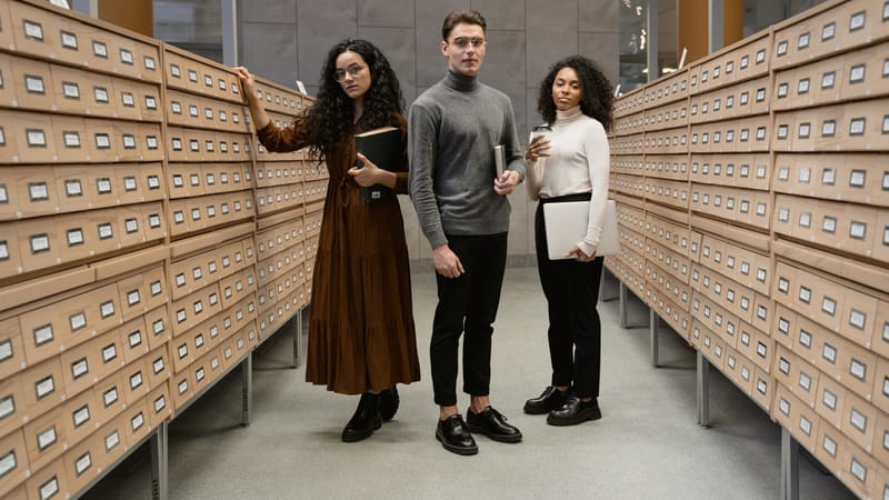 Trois étudiants divers effectuant des recherches dans le centre de catalogage de cartes d'une bibliothèque moderne.