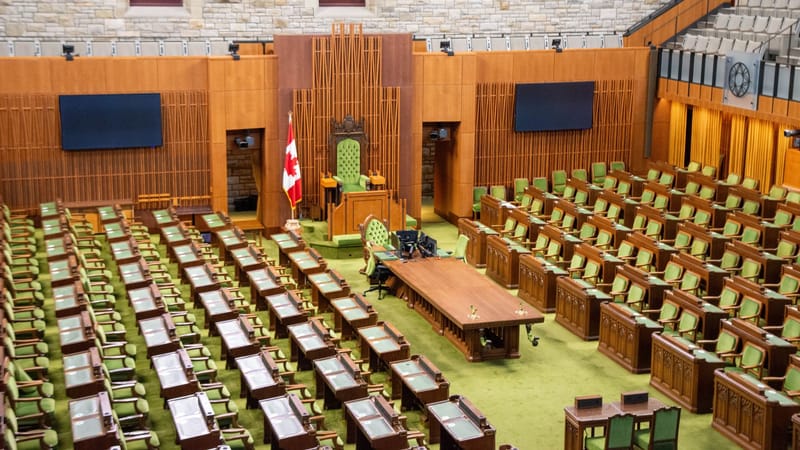 Vue intérieure de la Chambre des communes du Canada, avec ses sièges verts et son décor en bois.