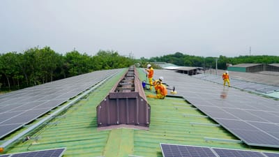 Équipe installant des panneaux solaires sur un grand toit sous un ciel dégagé, promouvant l'énergie renouvelable.