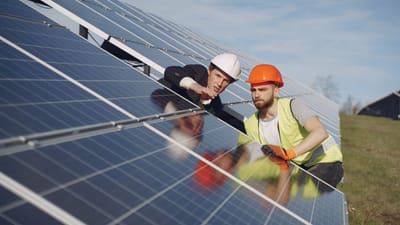 Deux techniciens inspectant des panneaux solaires dans un cadre extérieur ensoleillé.