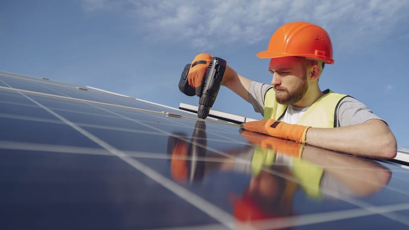 Ingénieur en casque de sécurité et vêtements de protection installant un panneau solaire à l'extérieur.
