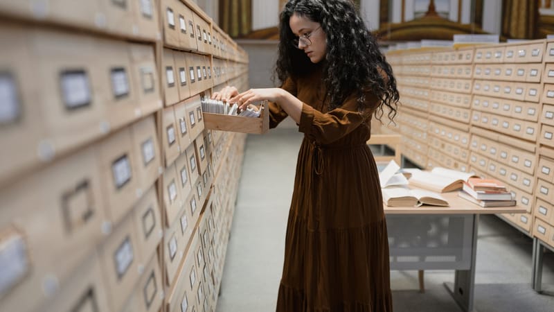 Une femme feuilletant un catalogue de cartes dans les archives de la bibliothèque, se concentrant sur la recherche et la collecte d'informations.