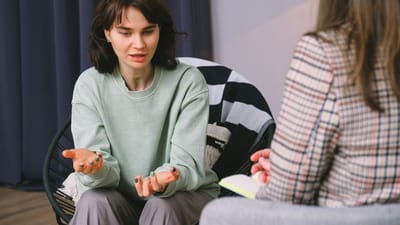 Deux femmes ayant une discussion réfléchie lors d'une séance de thérapie dans une ambiance de chambre cozy.