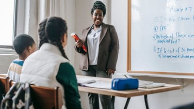 Un enseignant joyeux instruit un groupe diversifié d'élèves dans une salle de classe lumineuse.