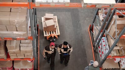 Vue en plongée de travailleurs d'entrepôt organisant et préparant des expéditions avec des boîtes et des palettes.
