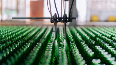 Bouteilles en verre sur une chaîne de production automatisée dans une usine, illustrant la fabrication industrielle du verre.