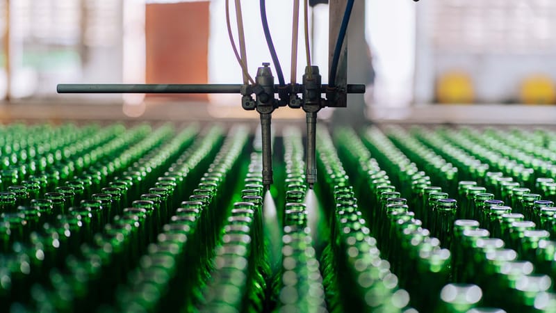 Bouteilles en verre sur une chaîne de production automatisée dans une usine, illustrant la fabrication industrielle du verre.