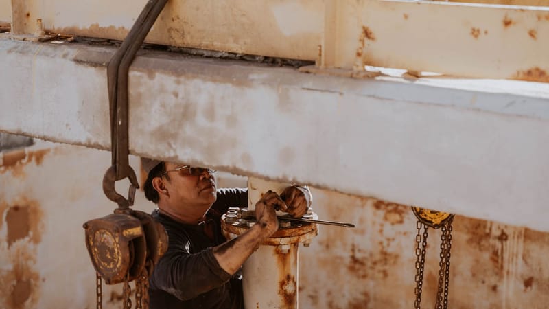 Un ouvrier libyen répare des machines industrielles en plein air par une journée ensoleillée.