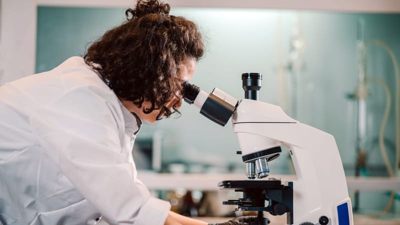 Une femme scientifique utilisant un microscope dans un environnement de laboratoire.