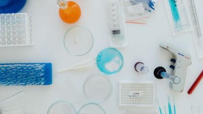 Vue de dessus de divers outils et contenants de laboratoire sur une surface blanche. Parfait pour du contenu lié à la science.