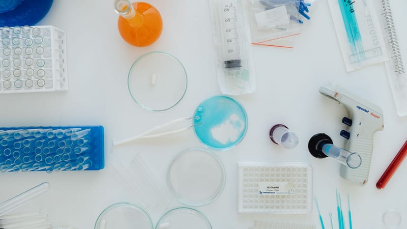 Vue de dessus de divers outils et contenants de laboratoire sur une surface blanche. Parfait pour du contenu lié à la science.