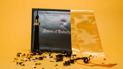 Gros plan d'un diplôme de graduation avec une frange et des confettis sur un fond jaune.