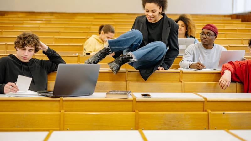 Des étudiants divers interagissent et étudient dans un amphithéâtre universitaire.