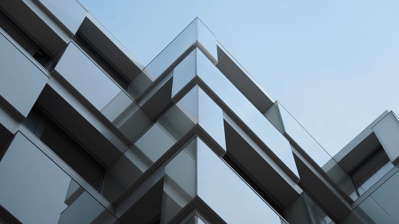 Prise de vue en contre-plongée de l'extérieur d'un bâtiment moderne avec des lignes géométriques et des éléments en verre.