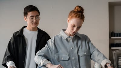 Homme asiatique et femme caucasienne collaborant sur la couture à l'aide de tissus et de motifs.
