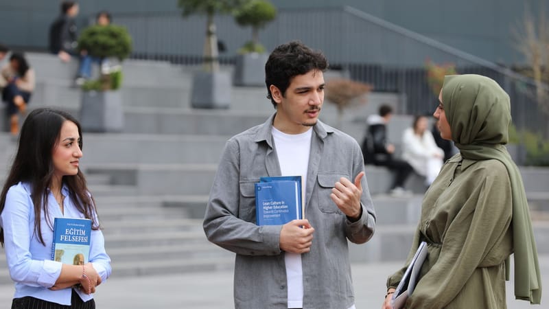 Trois étudiants discutent dans les escaliers du campus.